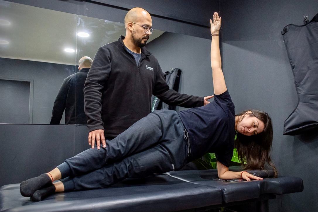Kinesiólogo de Evolve guiando un ejercicio de plancha lateral durante una sesión de rehabilitación activa